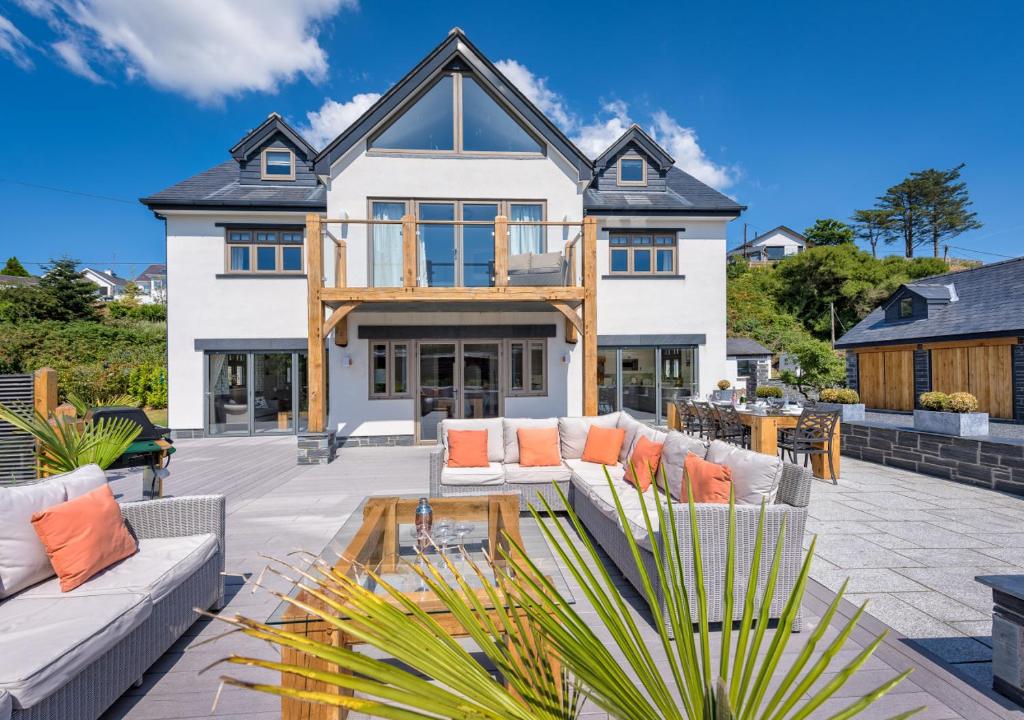 a large white house with a patio with orange pillows at Hafan Dawel in Abersoch
