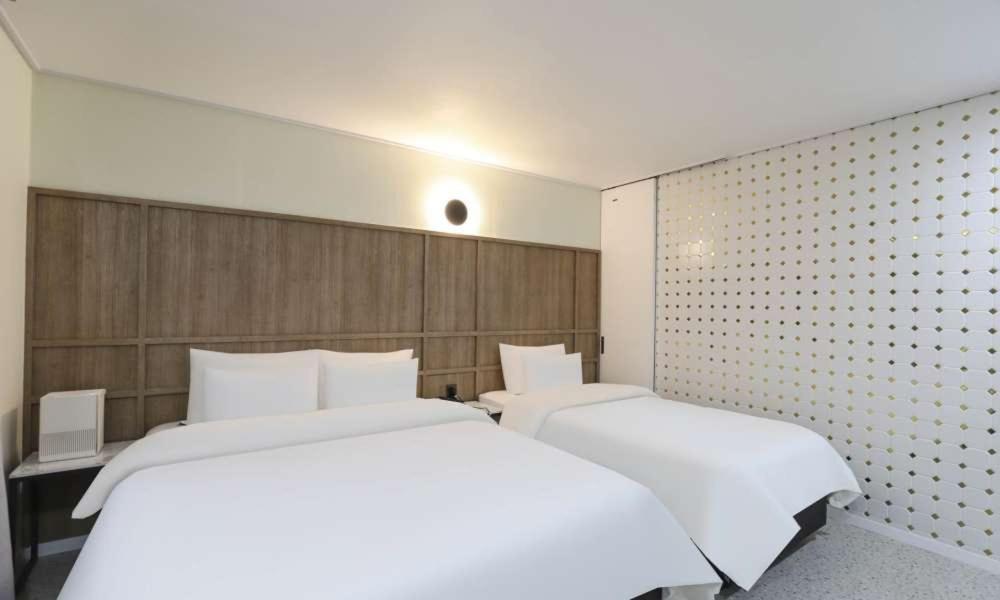 two beds in a hotel room with white sheets at JECHEON No 25 HOTEL in Jecheon