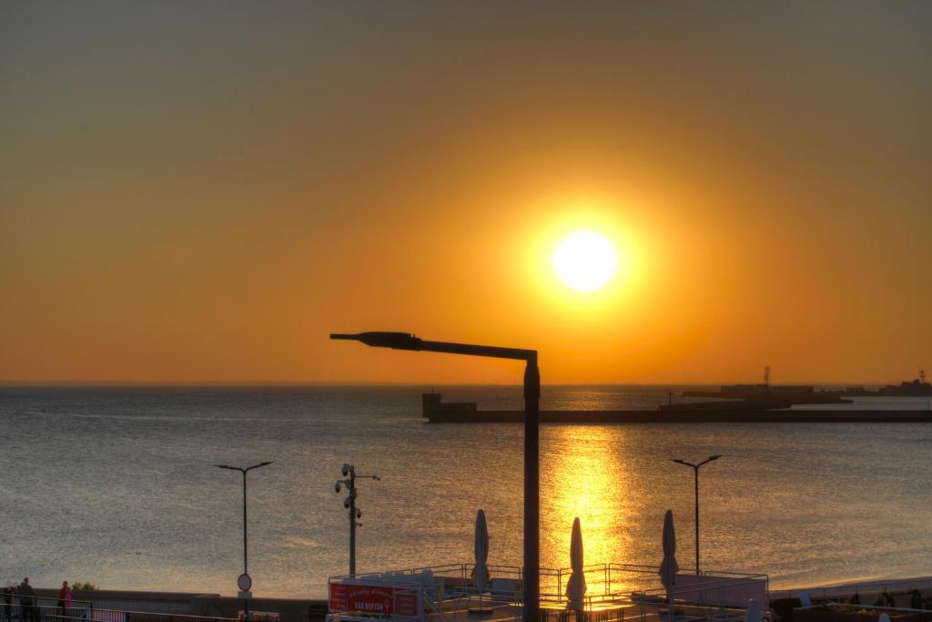 einen Sonnenuntergang über dem Meer mit Straßenbeleuchtung in der Unterkunft HelApart - z widokiem na morze in Hel