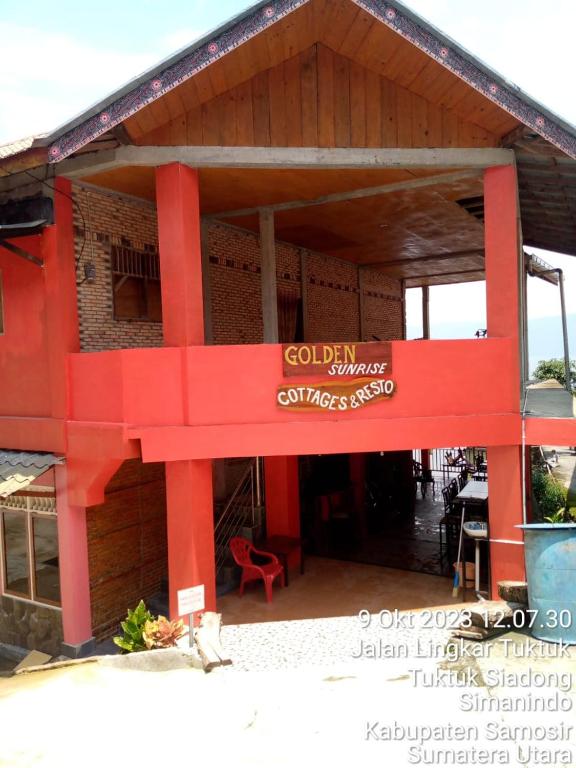 Un edificio rojo con un cartel al costado. en Thenewgoldensunrise, en Tuk Tuk