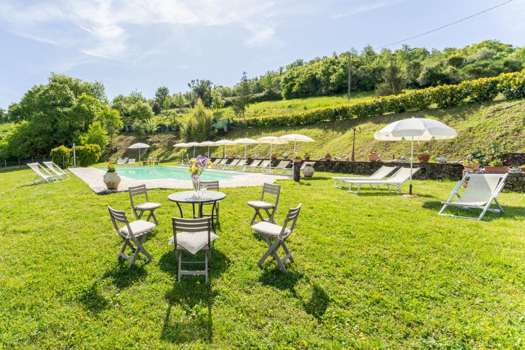 una mesa y sillas en el césped con una piscina en Apartment Marcigliana Front Pool Radicondoli, Siena, en Radicondoli