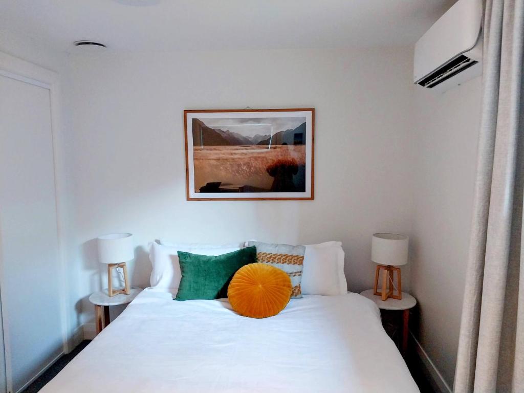 a bedroom with a white bed with an orange ball on it at City Fringe Apartment with garage in Wellington