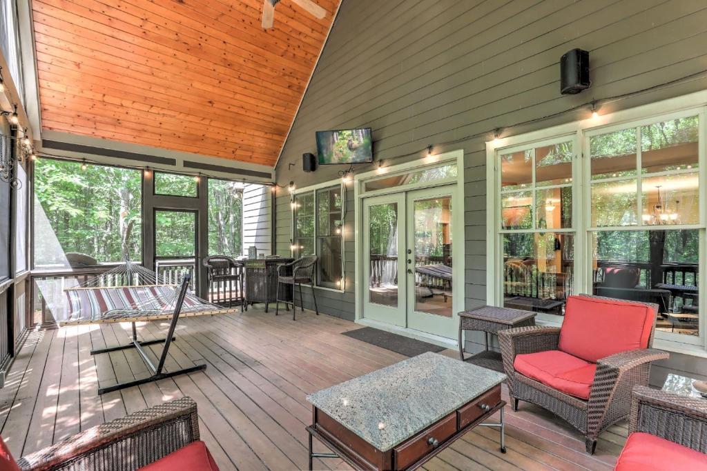 una casa con porche cubierto con sillas y TV en Stars Align Cottage - Relaxing Hot Tub Comfy Outdoor Seating More, en Afton