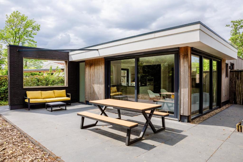 een patio met een picknicktafel en een huis bij Stijlvol ingerichte (4 pers.) bungalow in Baarland in Baarland