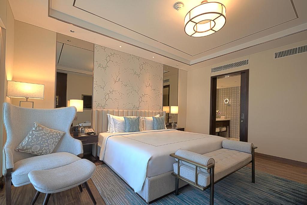 a bedroom with a white bed and a chair at Taj Bangalore in Devanahalli-Bangalore