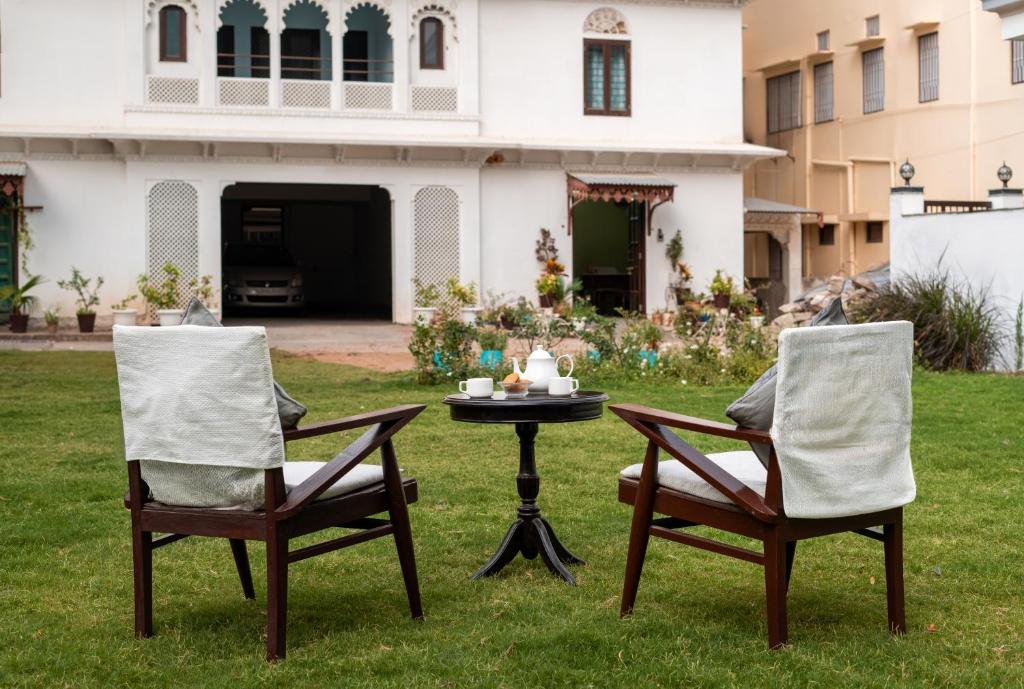dos sillas y una mesa frente a una casa en Chandra Vilas Heritage stay, en Udaipur