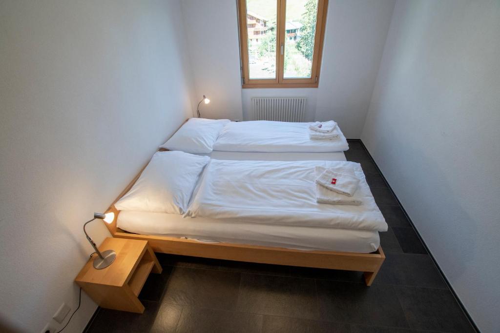 Habitación pequeña con 2 camas y ventana en Haus Bella Vista, en Riederalp