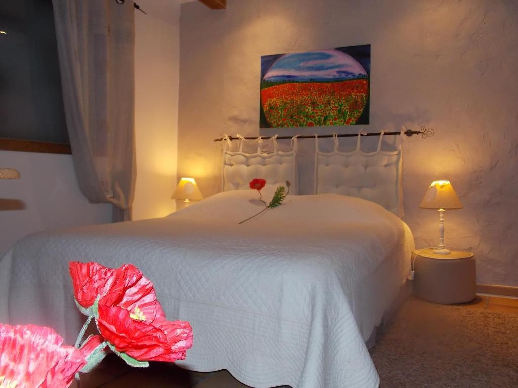 オプスにあるLa Maison Du Bonheurのベッドルーム1室(花の飾られた白いベッド1台付)