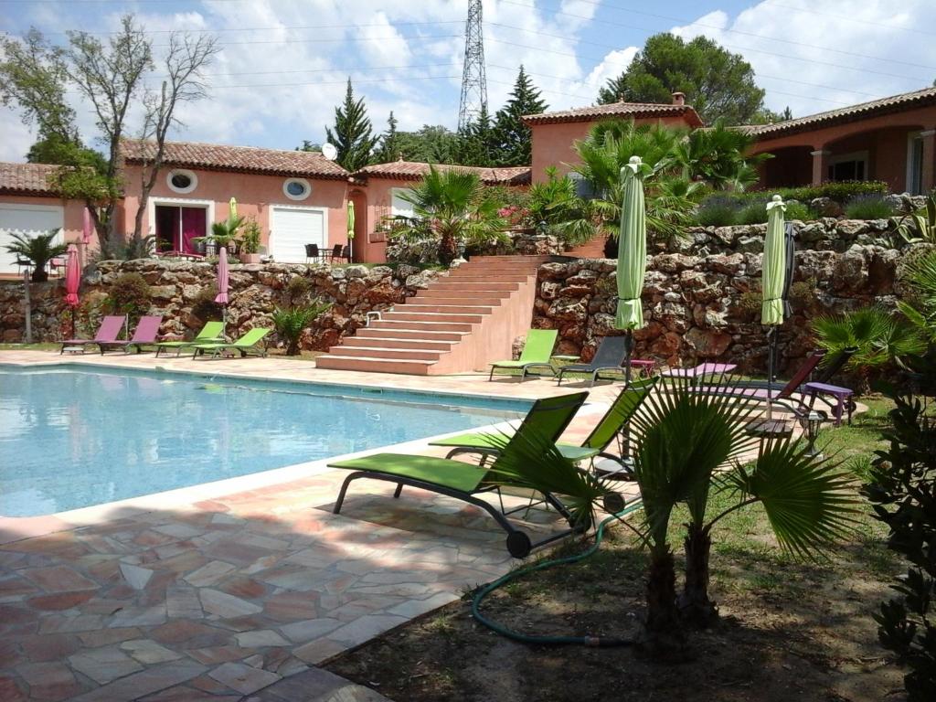 una piscina con sillas verdes y una casa en Mas des Lys, en Roquebrune-sur-Argens