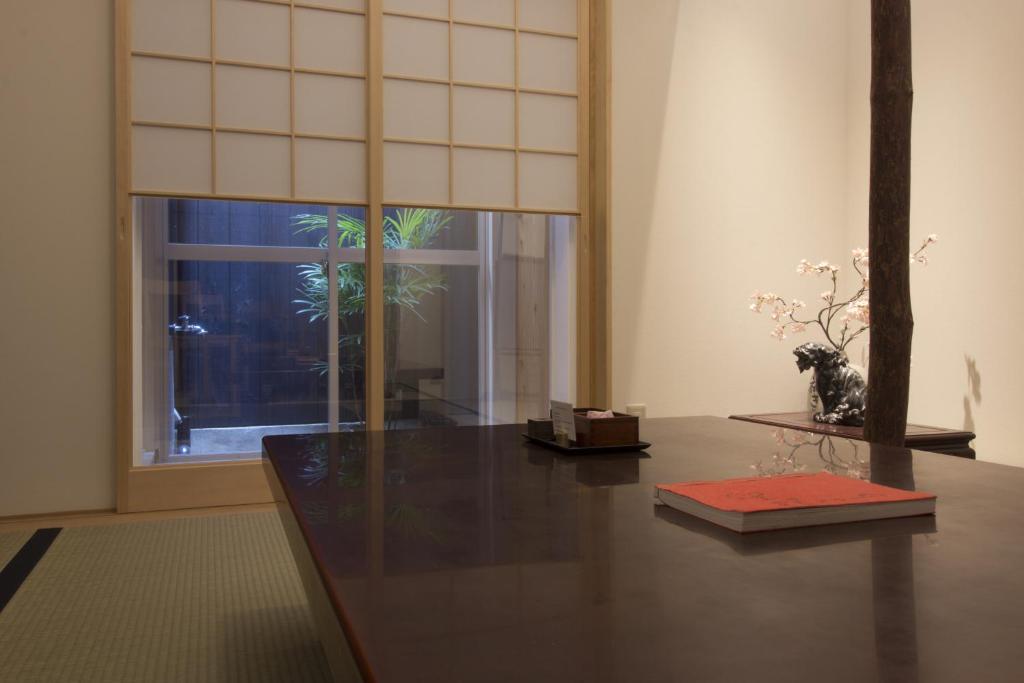 a room with a table and a window with a plant at Gion House in Kyoto