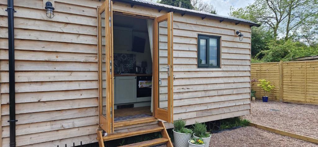 uma pequena casa com uma porta aberta num jardim em Cosy Owl - Shepherds Hut em Longford