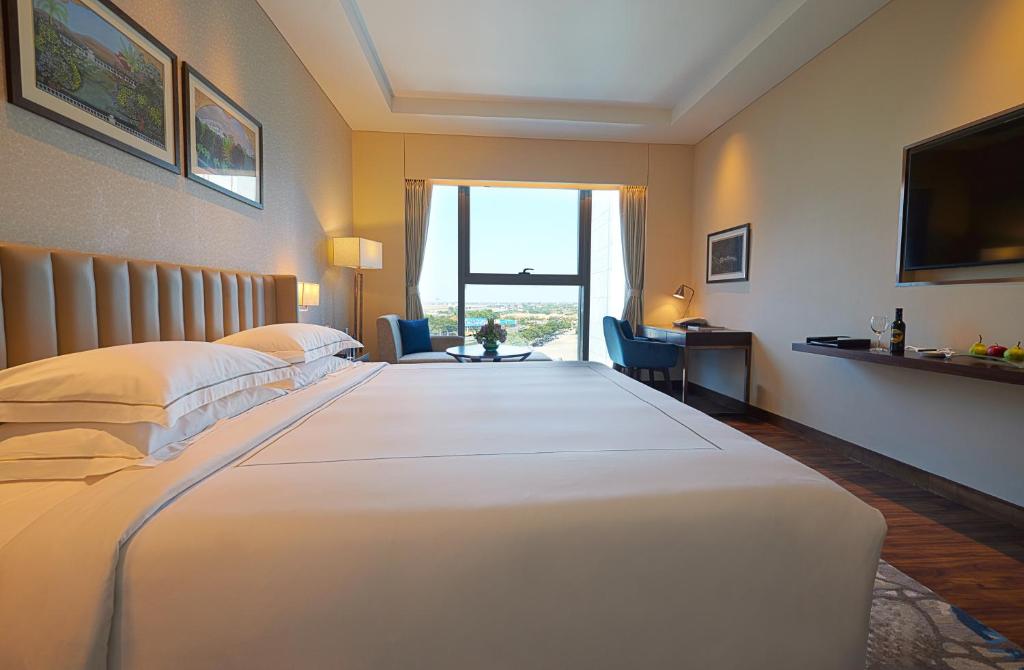 a hotel room with a large white bed with a window at Taj Bangalore in Devanahalli-Bangalore