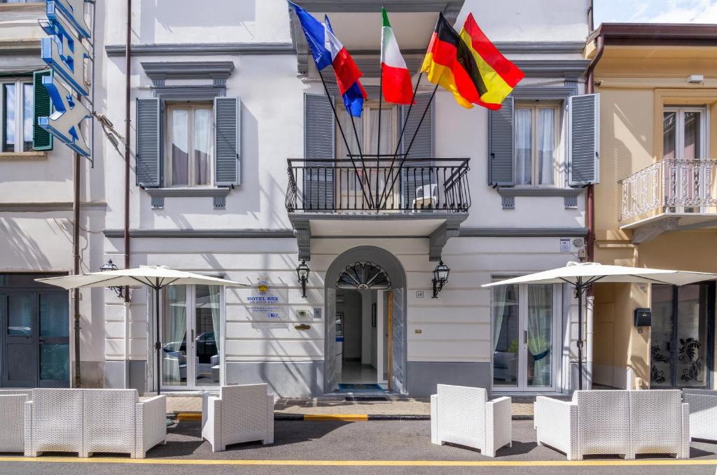 two flags on a building with chairs and umbrellas at Hotel Rex in Viareggio