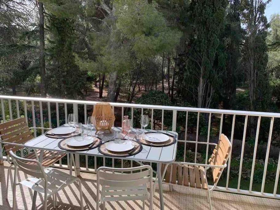 une table blanche avec des assiettes et des verres sur une clôture dans l'établissement Bandol plage de Renécros, à Bandol