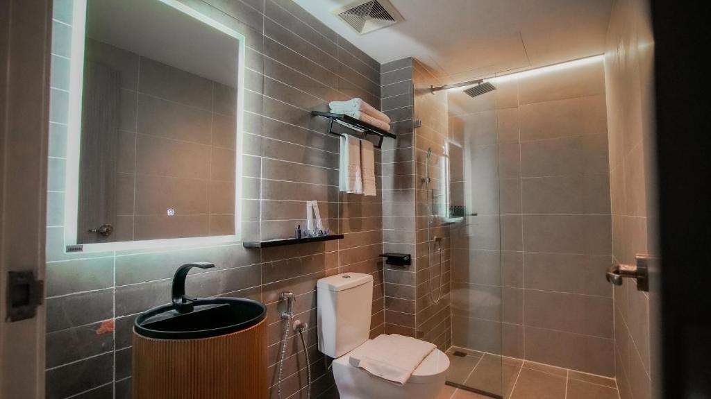 uma casa de banho com um WC e um chuveiro com um espelho. em Kozi Nest em Kuching