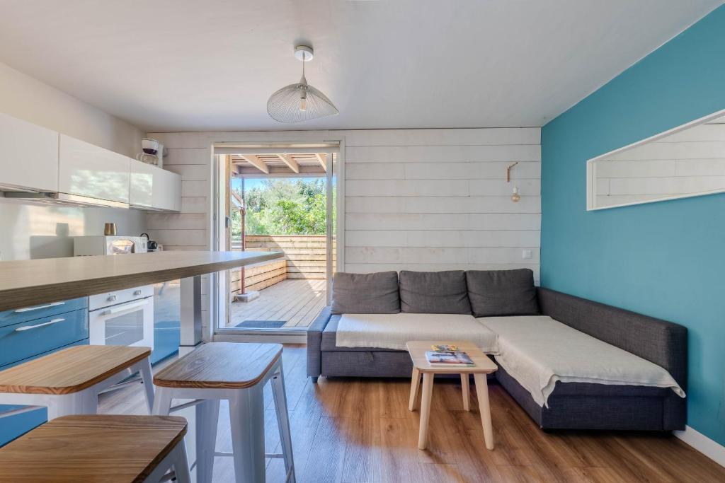 a living room with a couch and a kitchen at Appartement avec terrasse/Bord de mer/Idéal SURF in Seignosse