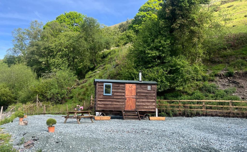 a tiny house with a picnic table and a bench at Berwyn Shepherds Hut in Wrexham