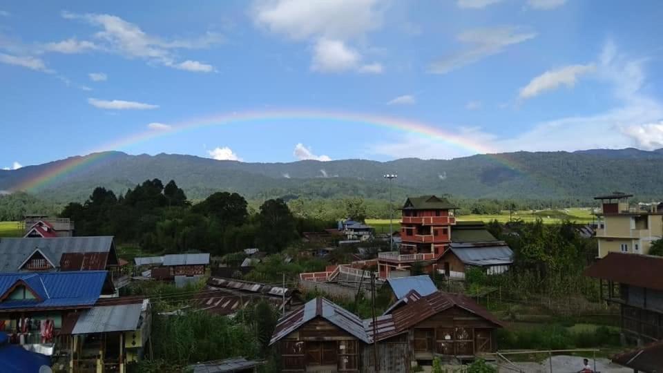 een regenboog in de lucht boven een dorp met huizen bij Arunachal Guest house in Hāpoli