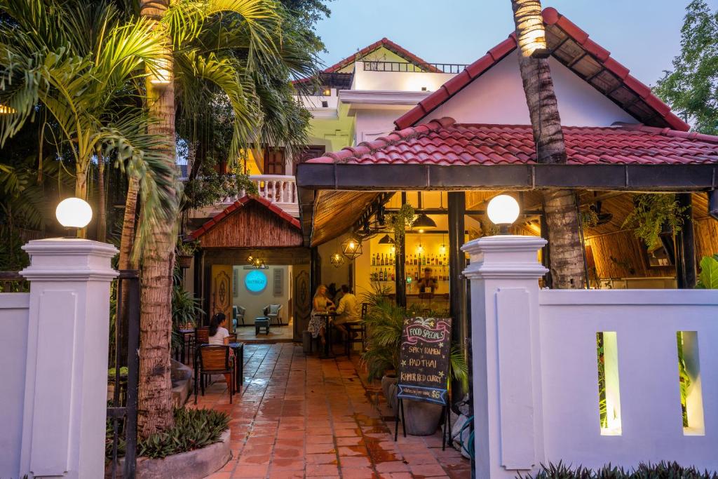 una casa con una puerta blanca y palmeras en River Retreat Boutique Hotel, en Siem Reap