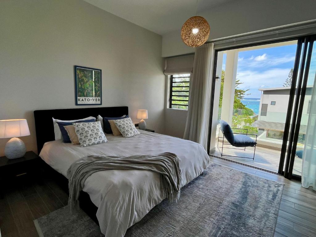 a bedroom with a bed and a large sliding glass door at Summer beachfront apartment in Belle Mare