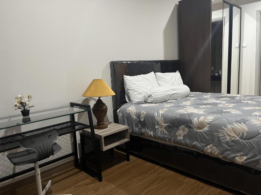 a bedroom with a bed and a desk with a lamp at DeAr Caspian Apartment in Surabaya