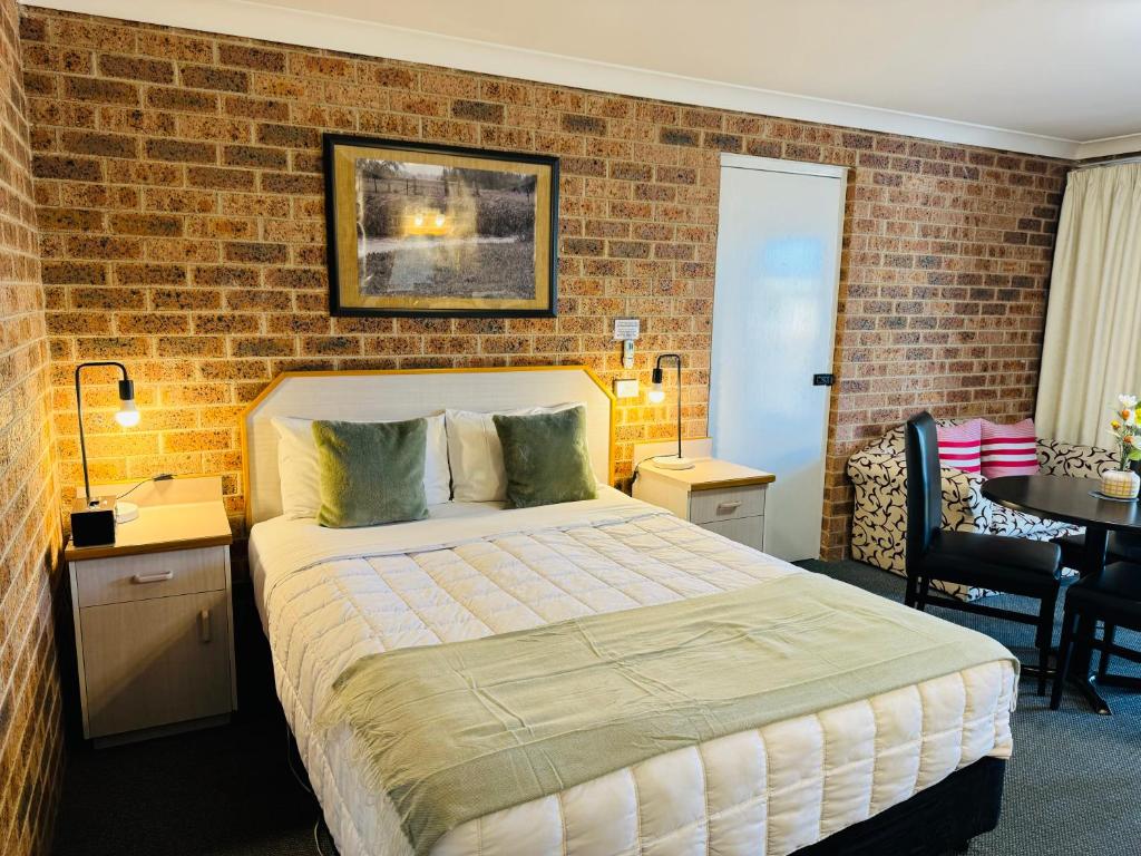 um quarto com uma cama e uma parede de tijolos em Town and Country Motor Inn em Tamworth