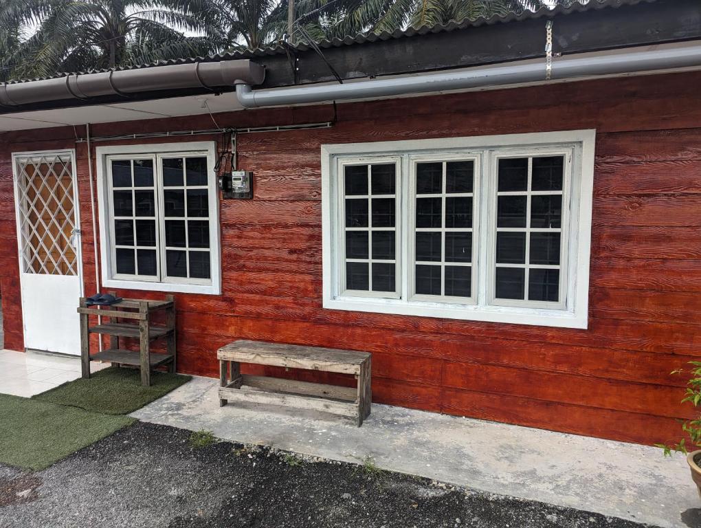 a red house with white windows and a bench at PULAU INDAH HOMESTAY in Pulau Indah