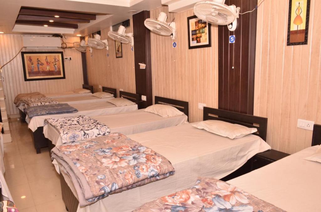 four beds lined up in a row in a room at Hotel Comfort Hostel Charbagh Inn Lucknow in Lucknow