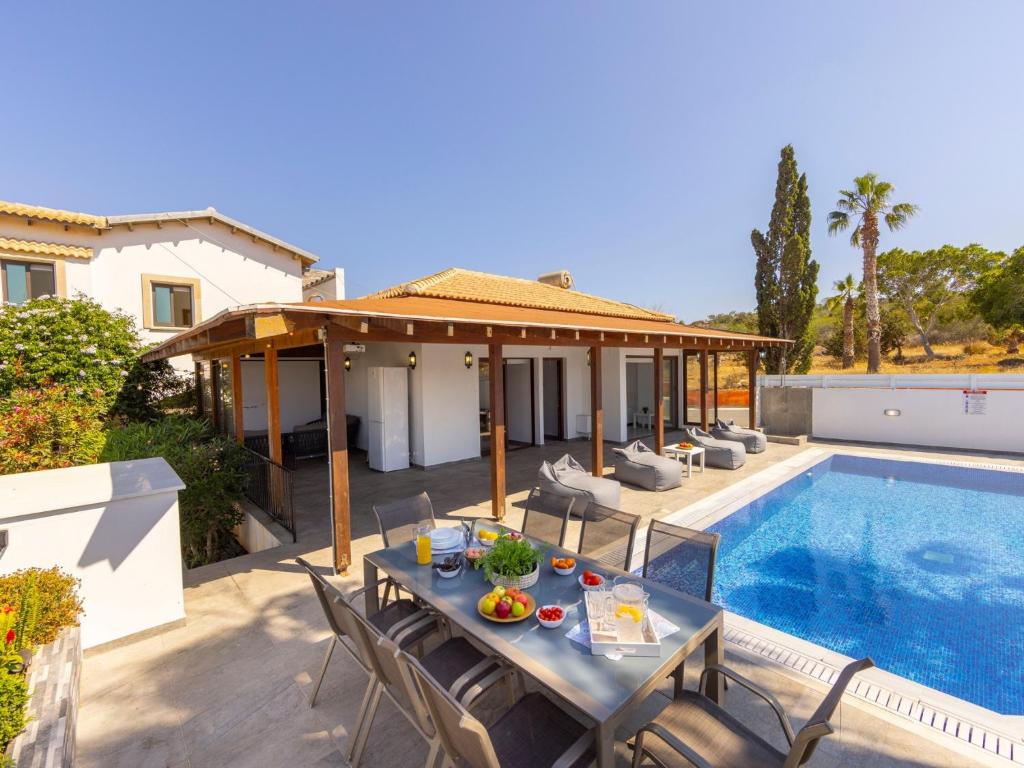a patio with a table and chairs next to a swimming pool at Villa Socrates in Protaras