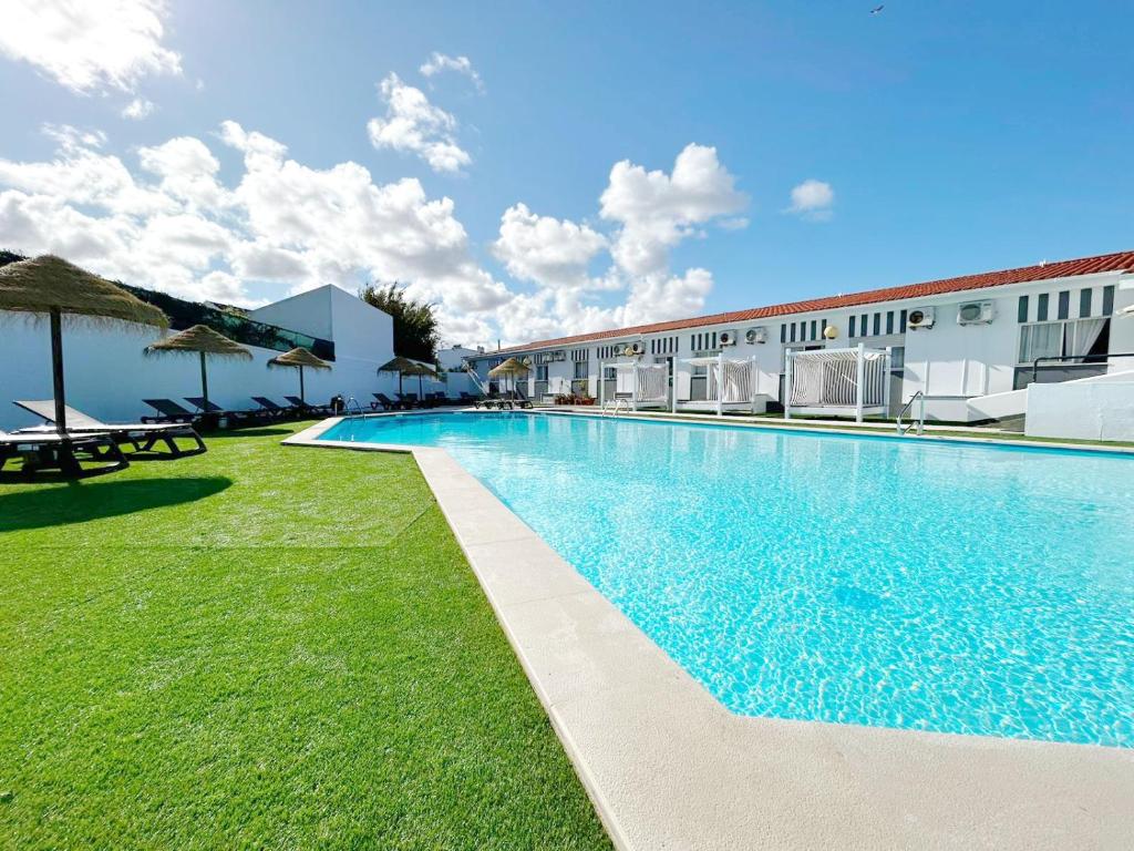 une piscine en face d'un bâtiment dans l'établissement Hotel HS Milfontes Beach - Duna Parque Group, à Vila Nova de Milfontes