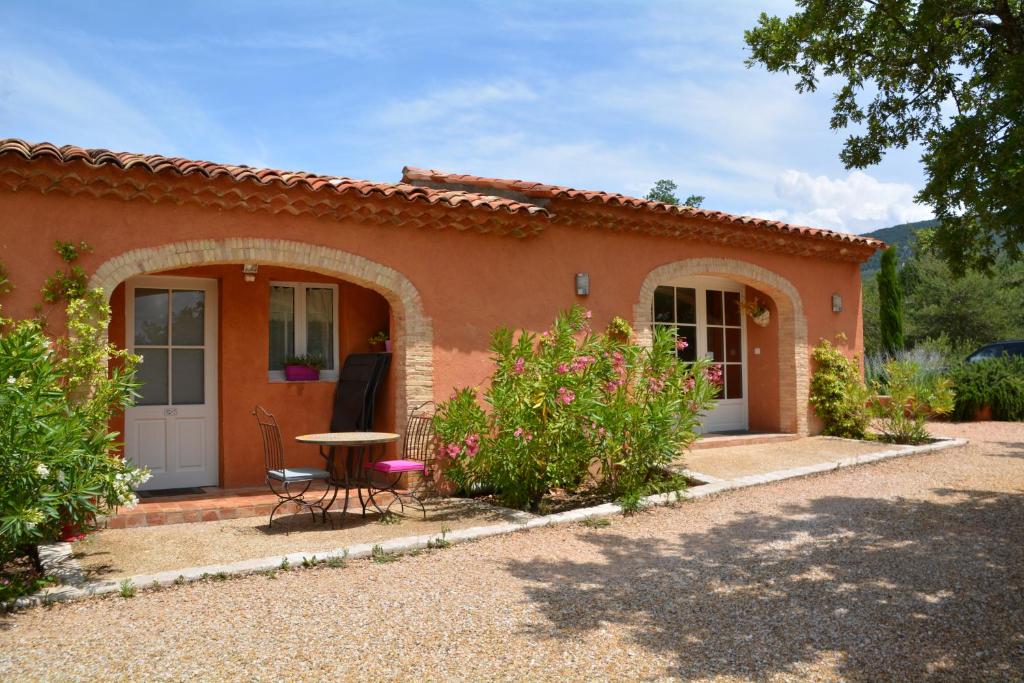 ein kleines orangefarbenes Haus mit einem Tisch und einem Stuhl in der Unterkunft Les Jardins de l'Ermitage in Les Salles-sur-Verdon