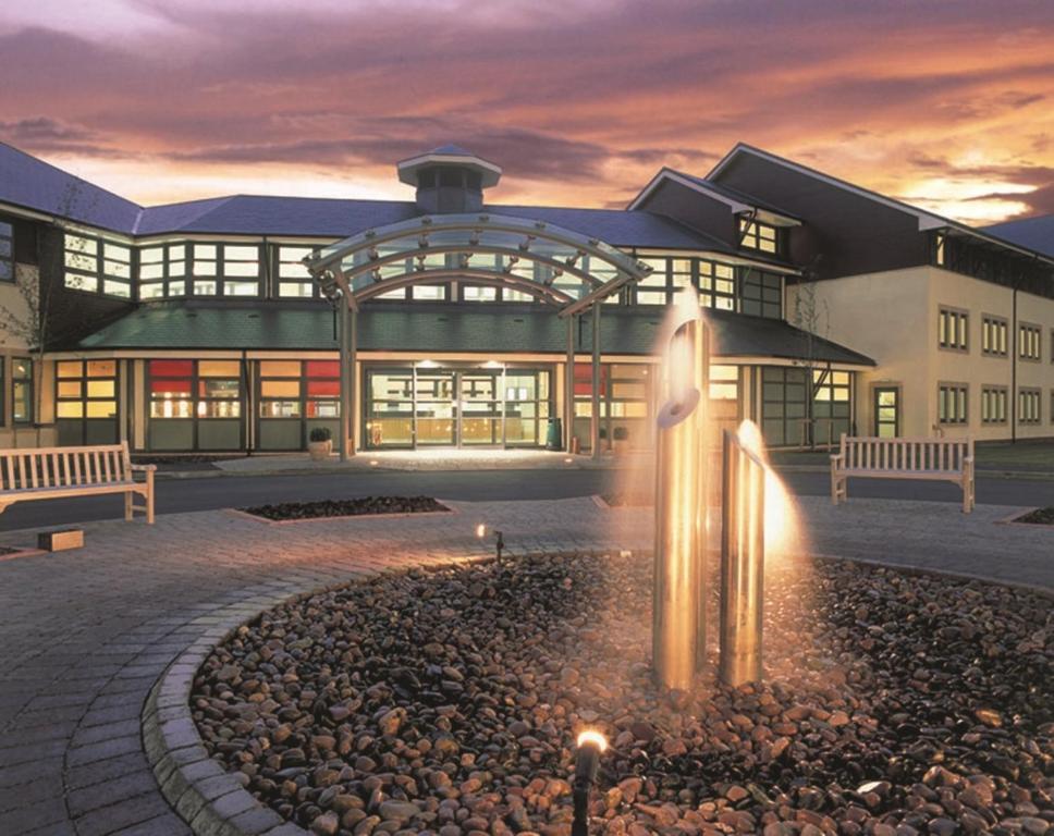 a large building with a fountain in front of it at Wychwood Park Hotel and Golf Club in Crewe