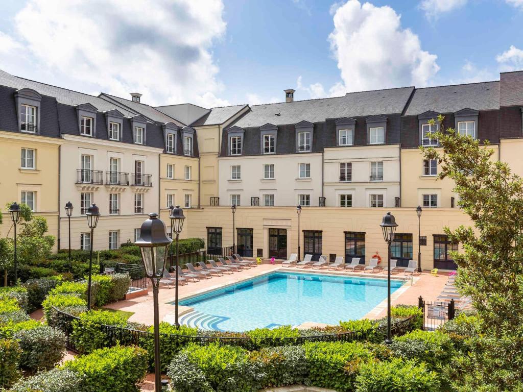 a large building with a pool in front of it at Disneyland Deluxe flat, outside pool, Climatisation, 1 min to Disney Parks in Serris