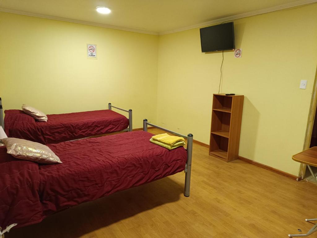 a room with two beds and a flat screen tv at Hostal El Tatio, habitaciones con baño privado in Calama