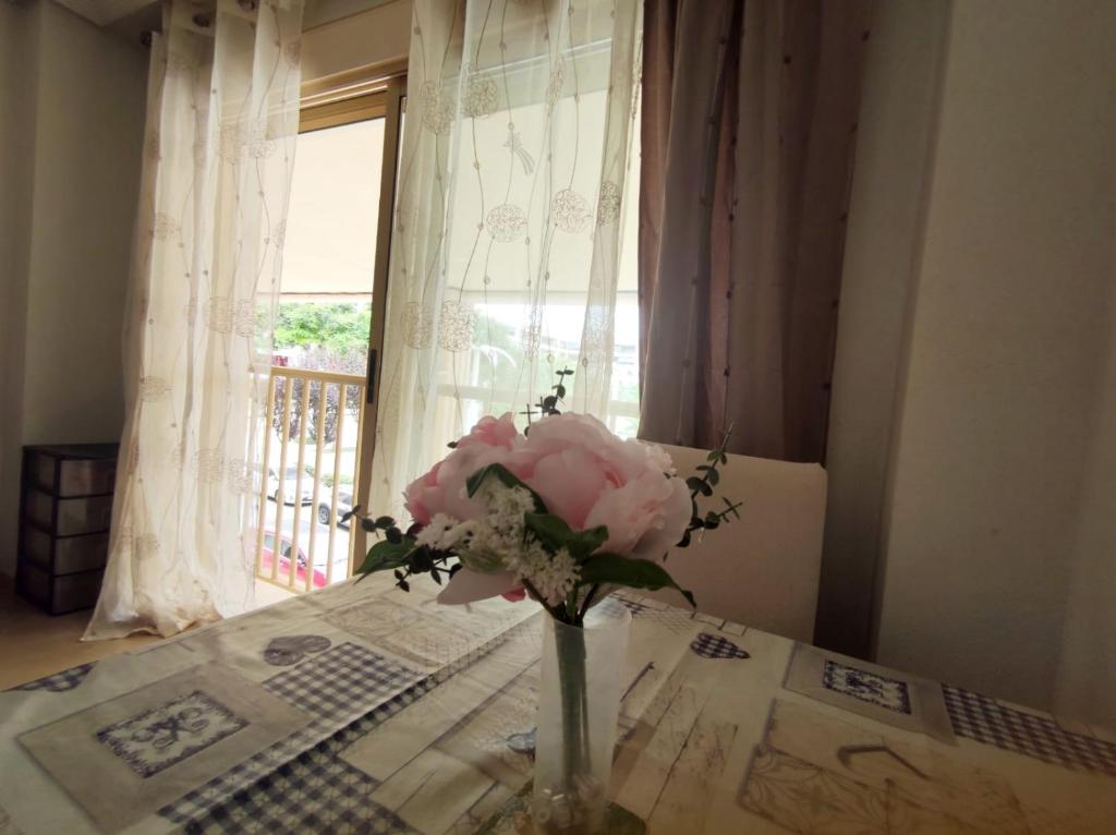 un jarrón de flores sentado en una mesa frente a una ventana en Plaza Porticada, en Guardamar del Segura