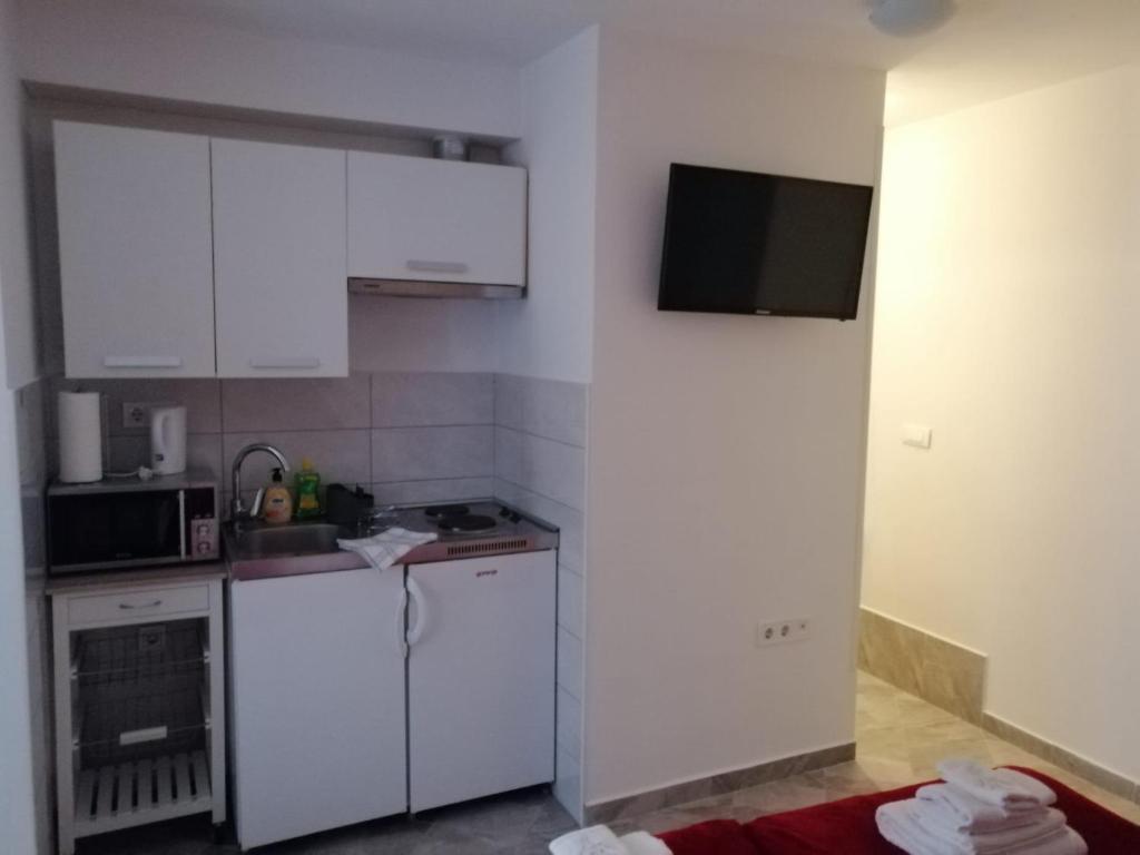 una pequeña cocina con armarios blancos y microondas en Studio Apartment Ana, en Zadar