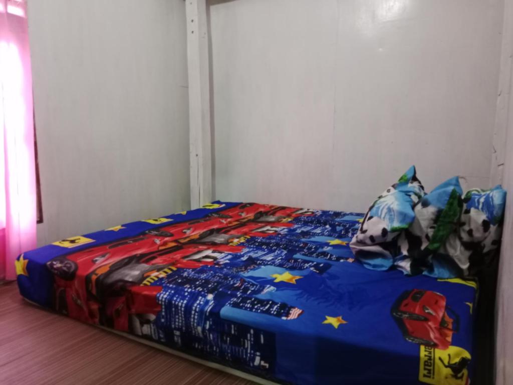 a bed with a blue comforter and pillows at Komodo homestay in Komodo