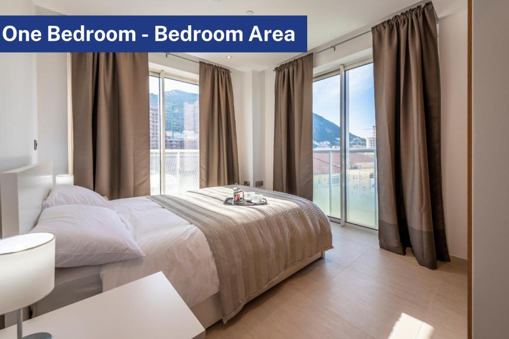 a bedroom with a bed and a large window at Bentley Holiday Apartments - West One in Gibraltar
