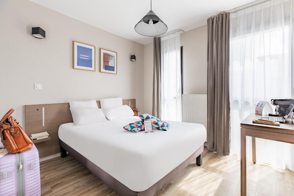 um quarto de hotel com uma grande cama branca e uma janela em Appart'City Confort Angers em Angers