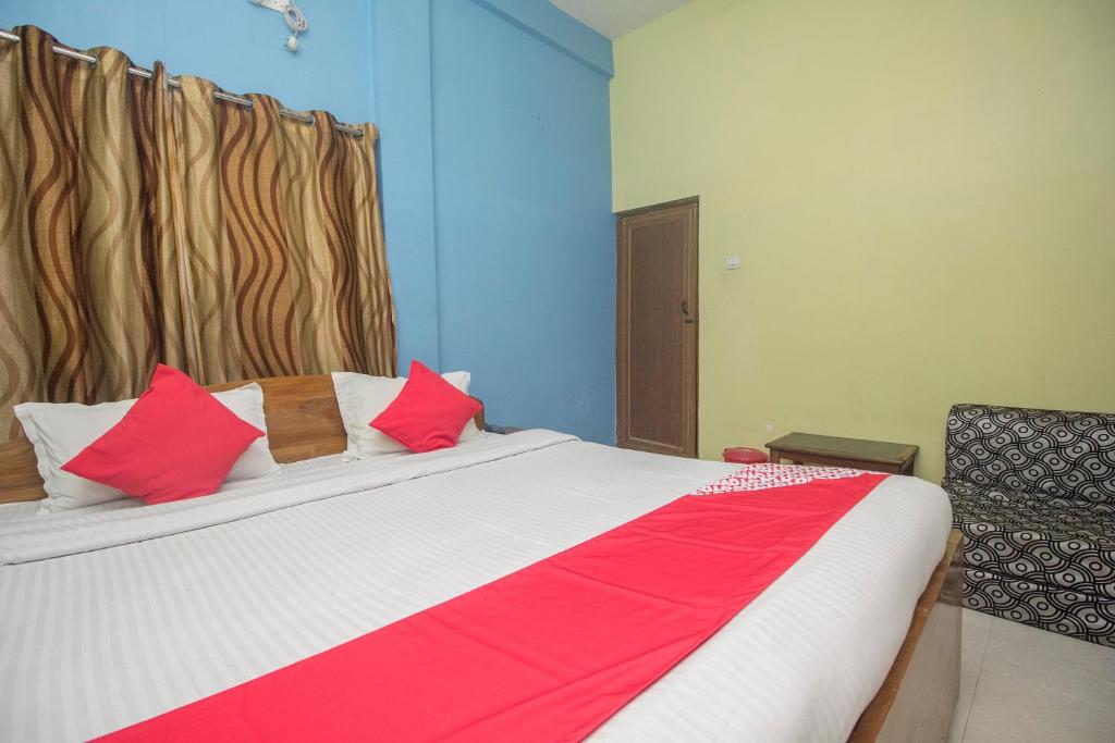 a bedroom with a large bed with red and white pillows at Collection O Dooars Dhaba And Restaurant in Hāsimāra
