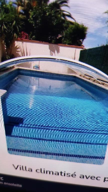 een zwembad met blauw water voor een gebouw bij villa climatisée avec grande piscine in Saint-Laurent-de-la-Salanque