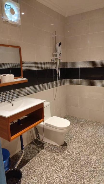 a bathroom with a toilet and a sink and a mirror at Hemingway Cottage 海明威度假屋 in Semporna
