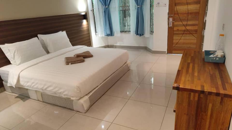 a bedroom with a white bed with a wooden headboard at Hemingway Cottage 海明威度假屋 in Semporna
