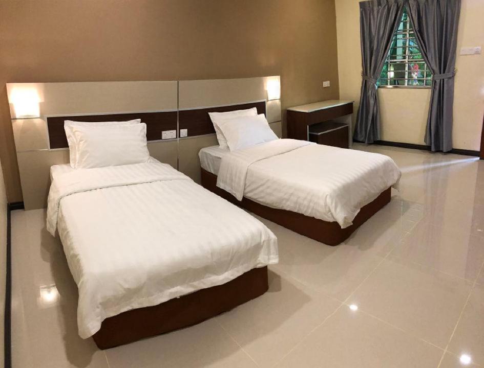 a hotel room with two beds and a window at Hemingway Cottage 海明威度假屋 in Semporna