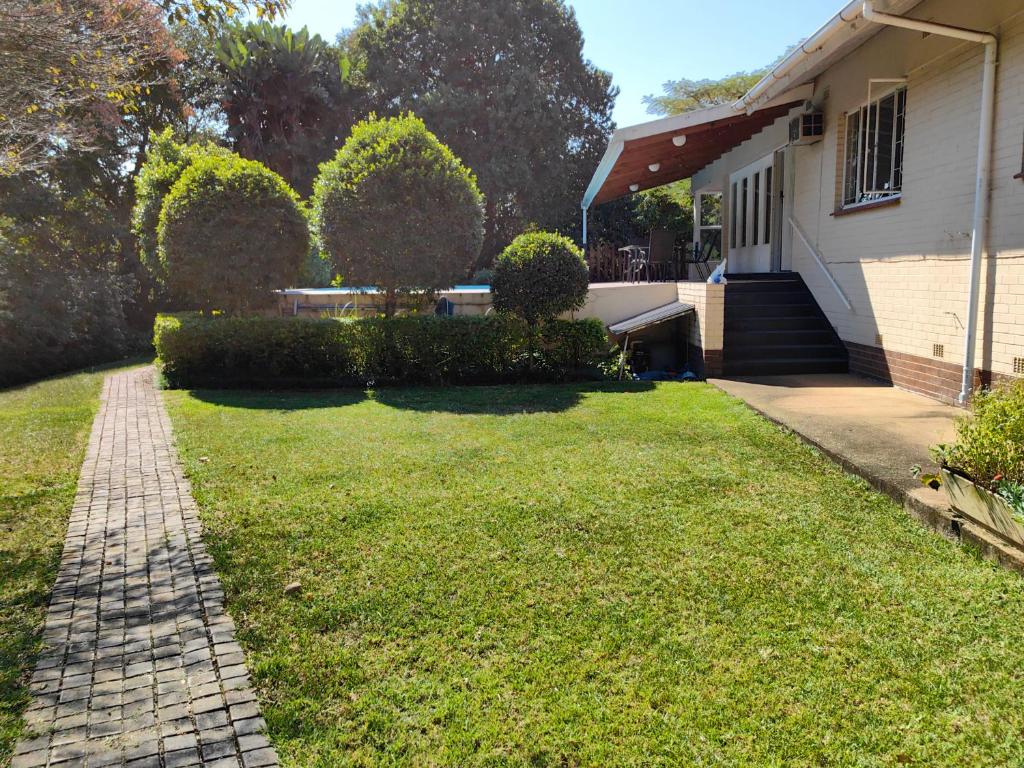 una casa con un patio de césped al lado de una casa en Thandanani Serene place, en Pietermaritzburg