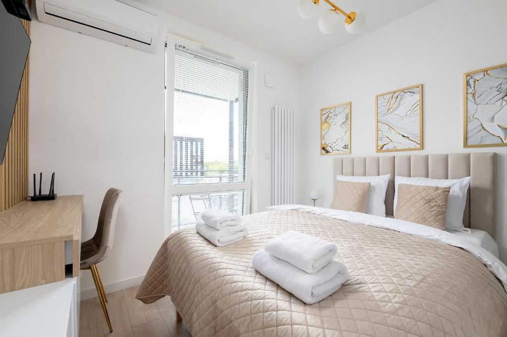 biała sypialnia z łóżkiem i ręcznikami w obiekcie RentPlanet - Apartamenty Wiktoryn w Warszawie