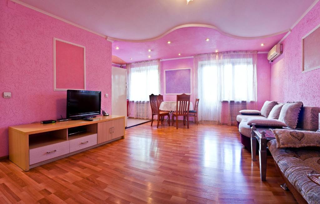 sala de estar con sofá y TV en Lessor Centre Apartments, en Almaty