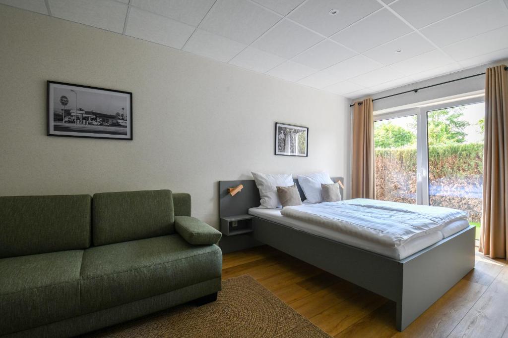 a bedroom with a bed and a couch and a window at Ammerhuus Boardinghomes in Edewecht
