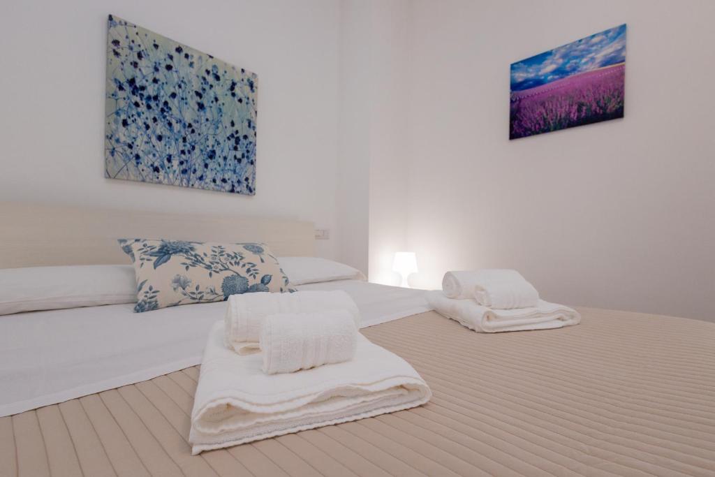 a white bedroom with two beds with towels on them at A Casa di Amici Apartment in Giardini Naxos