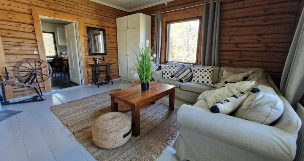 a living room with a couch and a table at Remontoitu suuri hirsitalo luonnon keskellä Nurmijärvellä in Perttula